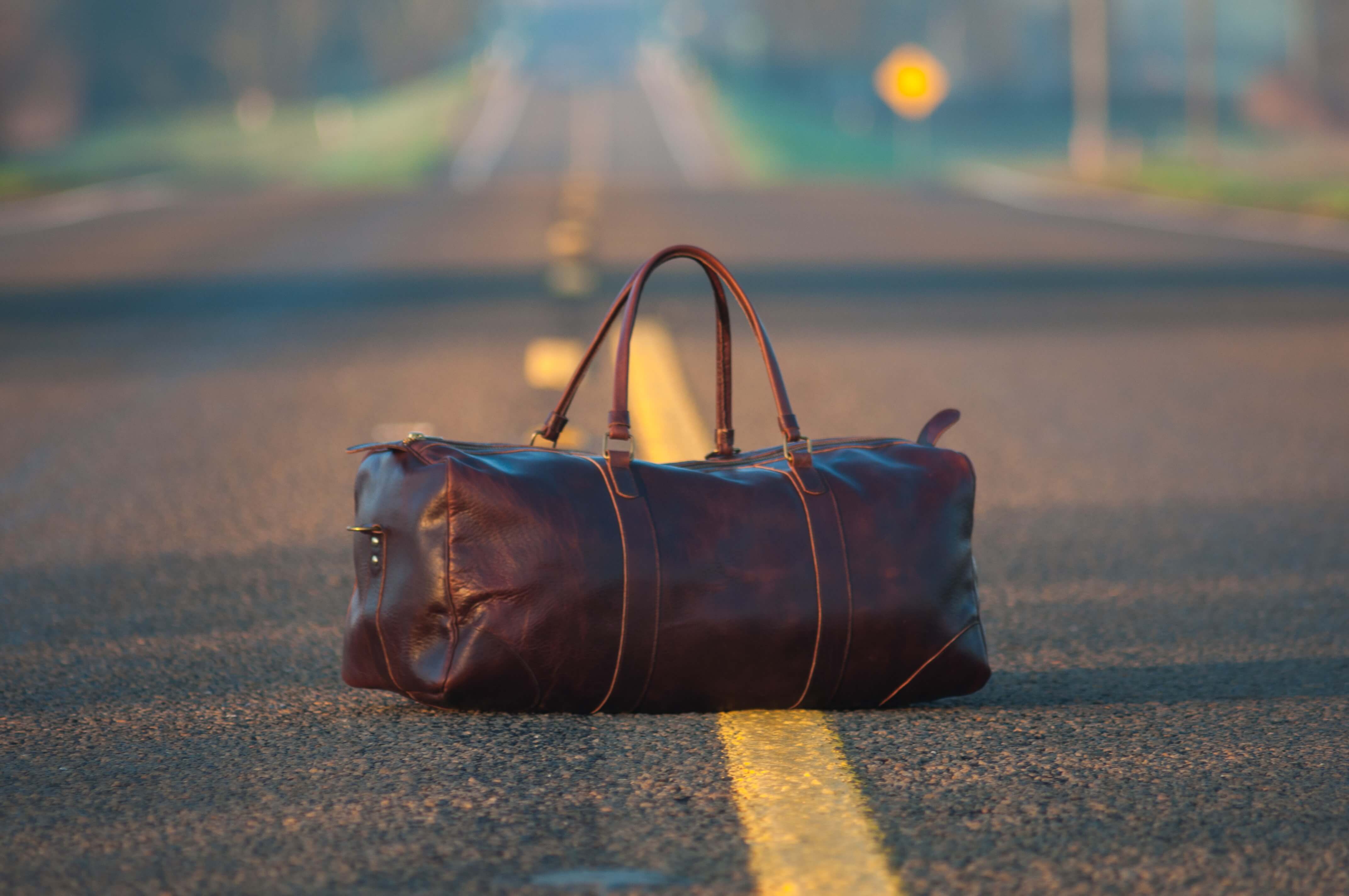 a brown leather bag in the middle of a road illustrates this story on Europe packing list